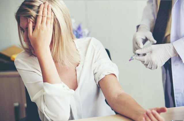 “Profissional de saúde a apoiar um paciente em contexto clínico, associado à fobia de agulhas e ansiedade médica.”